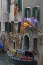 Flying flags of the Republic of Venice on a residential building, a gondola on the canal, Venice,