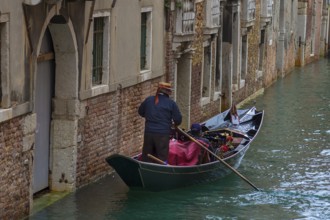 Gondolier with tourists on a canal tour, Venice, Veneto, Italy
