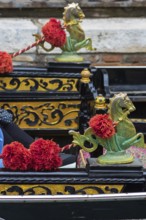 Mythological brass horse figures and red pompoms decorate the gondola, Venice, Veneto, Italy