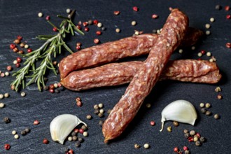 Rustic composition with salami, rosemary, peppercorns and garlic cloves, crunchy Pfefferbeiser