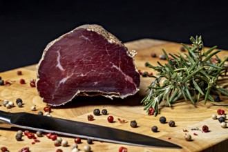 Delicatesswurst on wooden board decorated with peppercorns and rosemary, delicatess ham fresh from