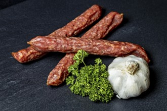 Simple arrangement with salami, parsley and a head of garlic, crunchy pepper sausage