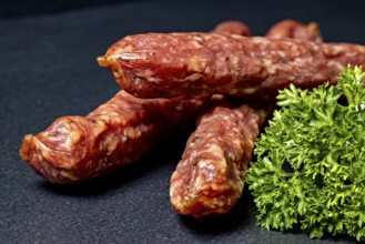 Close-up of salami with parsley on black background, crunchy pepperbite sausage