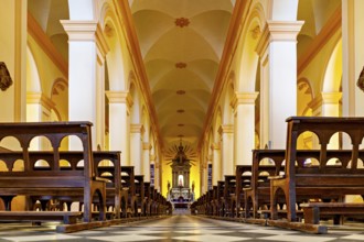 View along the aisle in a church interior with rows of seats, magnificent columns and an altar, the