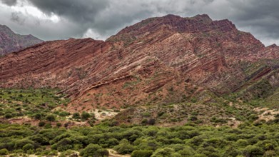 Red rocks dominate a green landscape under a dramatic sky, the landscape and colorful rock