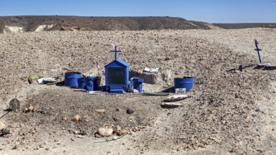 A blue grave with crosses in a barren desert landscape under a clear sky, grave in the Quebrada de