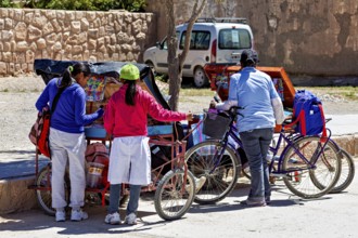 Three woman standing at roadside carts with bicycles, people in the streets of San Antonio de los