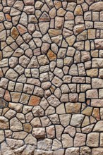 Irregular natural stone wall with brown-beige stones in rustic pattern, a natural stone wall as a