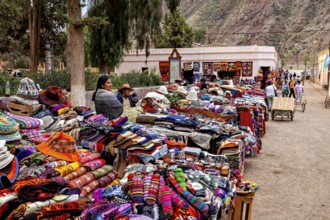 Merchants offer colorful clothes and goods at a market stand in mountainous surroundings, tourist