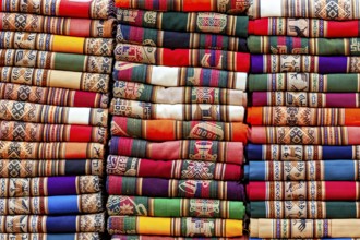 Stacked traditional cloths in bright colors and ethnic patterns, tourist and souvenir market of