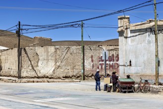 Small group of people talking on a street corner in a dry city with old buildings, San Antonio de