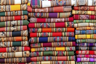 Close-up of stacked, colorful fabrics with traditional patterns, tourist and souvenir market of