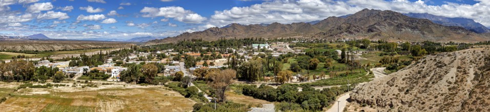 Panorama of a green village nestled in hilly and mountainous landscape, roads through the Quebrada