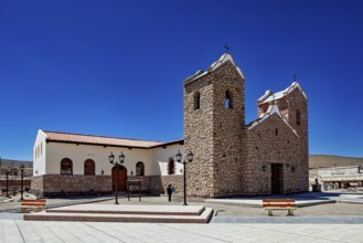 Stone church with two towers under clear blue sky in an open square with lanterns, Parroquia San