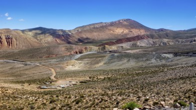 View of barren desert landscape with hills and mountains under clear skies, roads through the