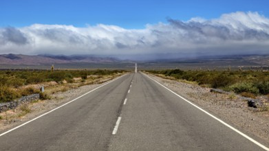Endless road leads to distant mountains under dramatic clouds, The landscape of the Quebrada with
