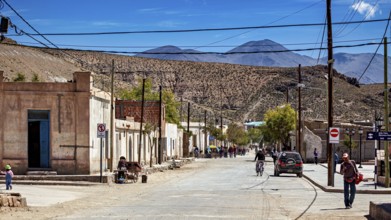 People and vehicles in a small desert town surrounded by rugged hills, San Antonio de los Cobres,