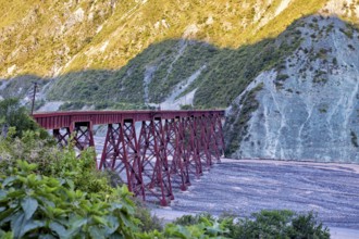 Red bridge over a dry riverbed in a mountainous landscape, roads through the Quebrada de Cafayate