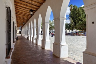 Long arcade with wooden ceiling, combines interior with a sunny square, The arcades of Cachi in