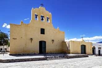 Yellow church with bell tower and cross against a clear sky, colonial style of architecture,