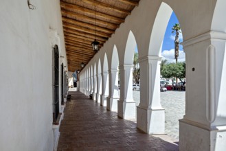 Corridor with arcades and wooden roof, leads outdoors in sunny weather, The arcades of Cachi in