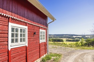Red wooden rural barn with a scenic landscape view in the countryside a sunny summer day, Sweden