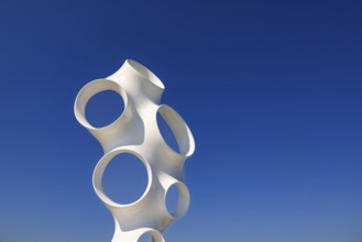 Contemporary white abstract sculpture composed of smooth tubular forms with large circular openings