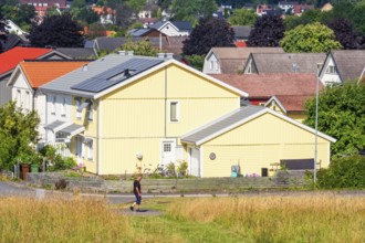 Alone man walking on a walkway in a residential area with wooden houses a sunny summer day,