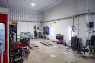 Empty car body shop interior with lifts, paint booth, tools and spare parts on carts and cabinets,