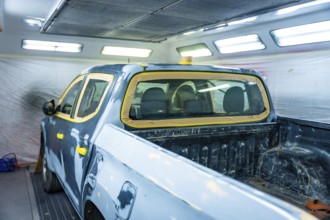Truck body masked and prepped inside a professional automotive paint booth, showing meticulous