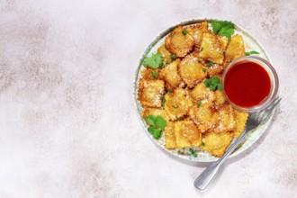 Fried ravioli with parmesan cheese, served with red sauce and garnished with herbs, on a light