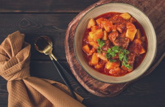 Stew with potatoes, in tomato sauce, with spices and herbs, close-up, no people, on a black