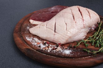 Fresh raw duck breasts, on a wooden chopping board, with herbs and spices, no people