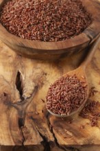 Natural, red rice, in a wooden bowl and spoon on a wooden surface in rustic style, top view