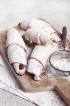 Bagels with filling, sweet pastries, sprinkled with powdered sugar, on a wooden board, dessert,