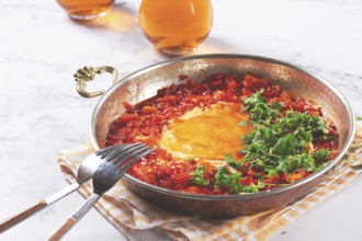 Traditional Turkish dish, scrambled eggs with tomatoes, Menemen, with herbs, in a frying pan,
