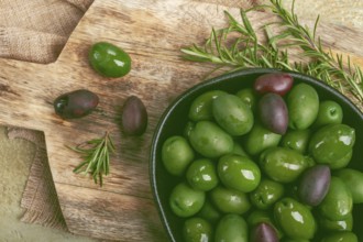 Chalkidiki olives, classic Greek green olives, in a bowl on a cutting board, top view, without