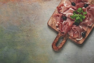 Sliced prosciutto, on a cutting board, with olives and herbs, snack, breakfast, no people