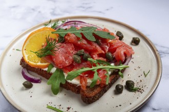 Sandwich with freshly smoked salmon, on black bread, with cottage cheese, with herbs and red