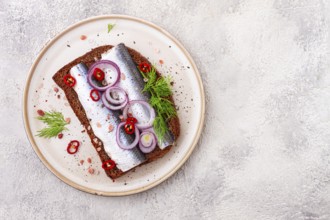 Sandwiches, Herring fish, on dark rye bread, sprinkled with onion, chili pepper and herbs, on a