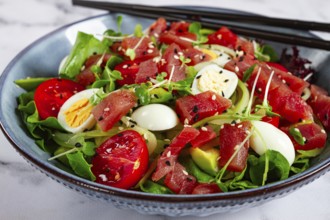 Salad with fresh tuna, cherry tomatoes and quail eggs and avacado, served with chopsticks