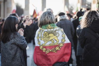 A woman wrapped in a flag of Iran during the Pahlavi period during the demonstration by exiled