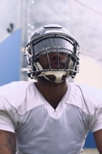Close-up of a focused American football player in action, wearing a reflective helmet and white