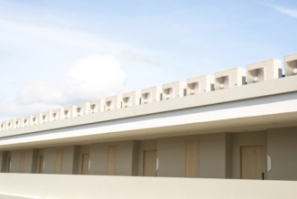 A minimalist building showcases its clean lines and neutral tones under a bright blue sky with