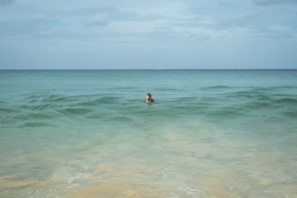A young woman enjoys a swim in the clear turquoise waters of a tranquil beach in vacation, creating