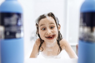 A joyful child enjoys bath time, playfully covered in foam and surrounded by bubbles, exuding