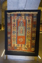 Colorful, traditional rug with detailed patterns displayed in a room, Sultanhani caravanserai, on