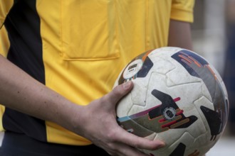Close-up of a referee holding a ball just in front of the start of a soccer game