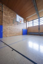 Large sports hall with basketball hoop, wooden walls and brick walls, bright lighting, Schlehengäu