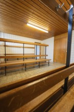 An empty changing room with wooden benches and simple lighting, Schlehengäu Grund Schule Gechingen,